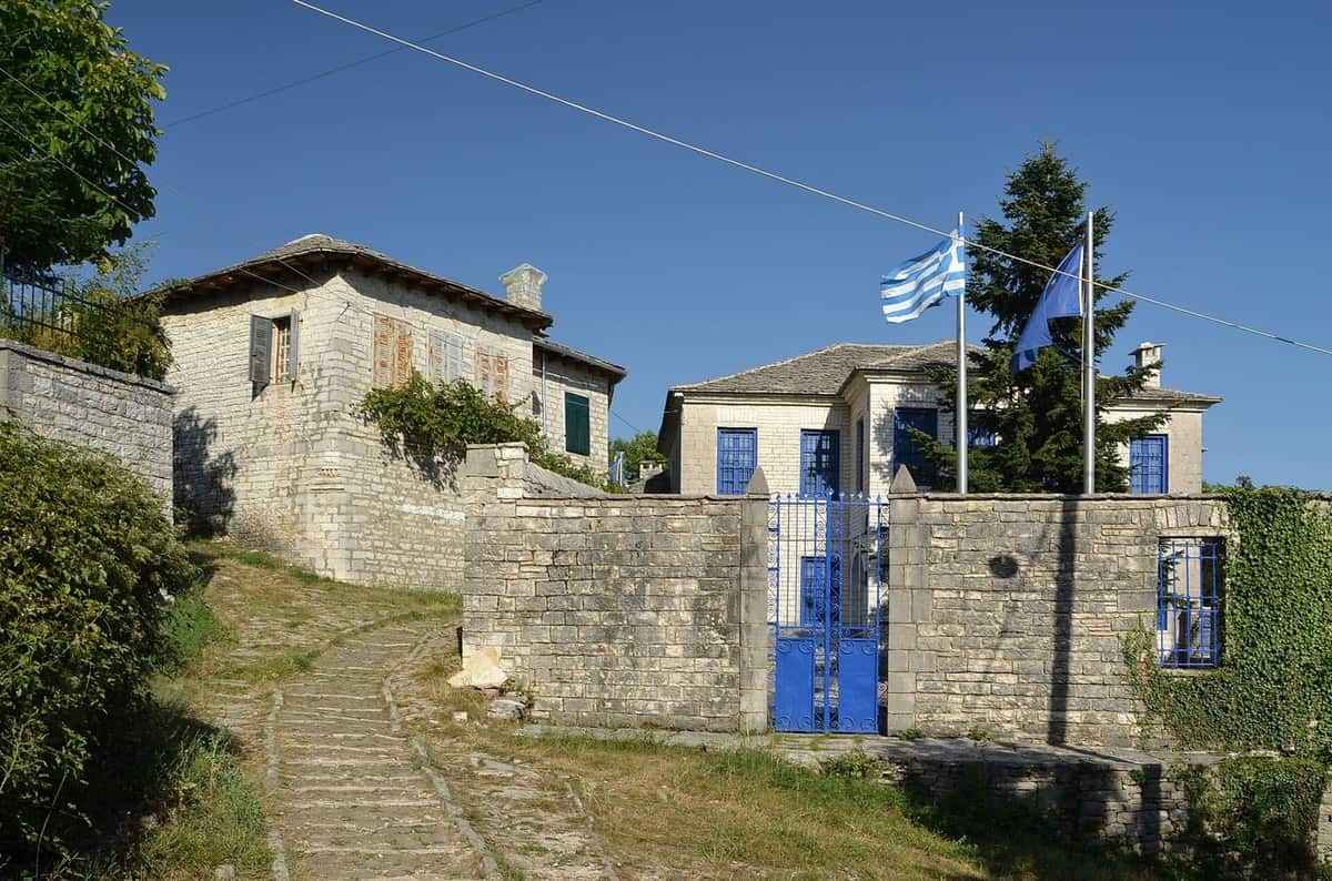 Πέτρινα κτίρια και καλντερίμι στο Μονοδένδρι με γαλάζιο ουρανό